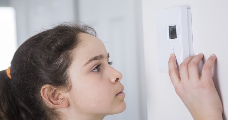 Teen Adjusting Thermostat On Central Heating Control central heating