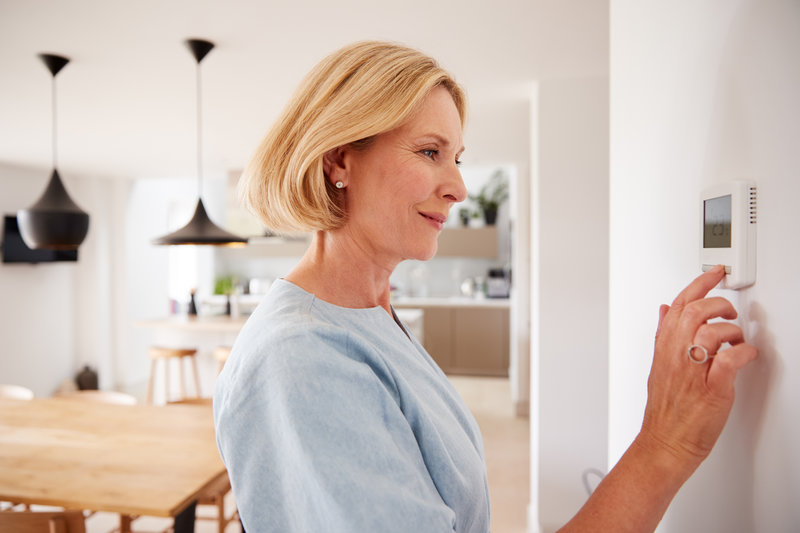 woman adjusting control heat pump