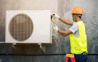 man servicing heat pump outdoor unit