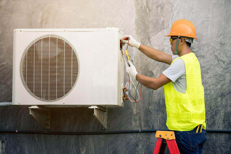 man servicing heat pump outdoor unit