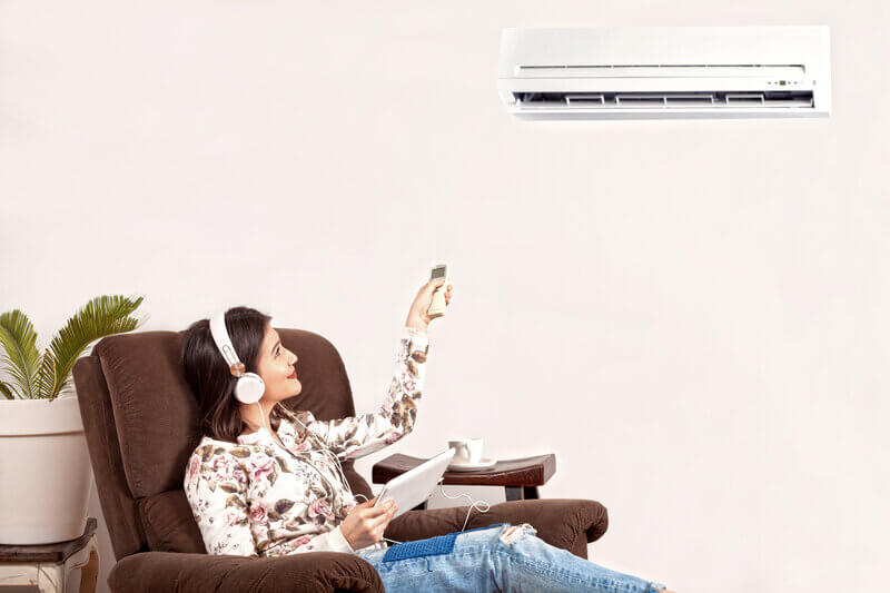 Woman using remote for heat pump control.