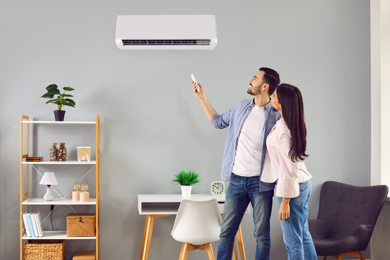 Couple turning on heat pump in living room